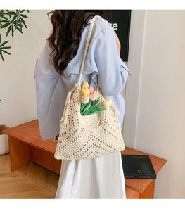 Detailed side view of cream woven tote bag featuring decorative tassels and hollow pattern