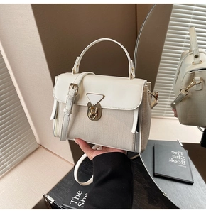 Detail der weißen Handtasche aus Leder und Webstoff mit goldenem Schloss und Griff