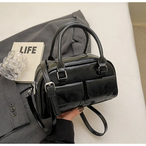 Close-up of black oily leather Boston bag with silver hardware and front flap pockets