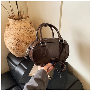 Détail d'un sac Boston marron foncé brillant avec poignées sur un fond d'art vintage