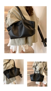 Detail of black pebbled leather tote bag with elegant gold metal buckle closure