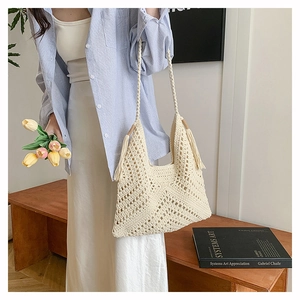 Detail of cream crochet shoulder bag featuring fringe accents and hollow geometric patterns