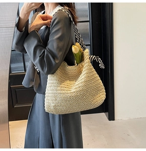 Détail du sac cabas en paille tissé main avec ruban rayé noir et blanc sur la bandoulière