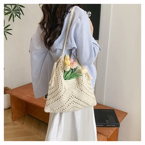 Detail of hand-crocheted beige woven tote bag with wavy patterns and tassel charm