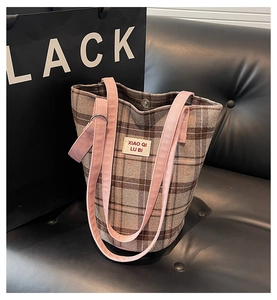 Detail of checkered bucket tote bag with pink straps and metallic snap button closure