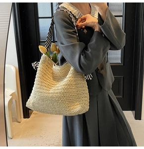 Détail du sac cabas en paille tissée avec foulard en soie rayé enroulé autour de l'anse