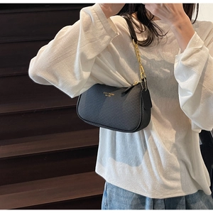 Détail du sac noir en cuir tressé avec logo doré et bandoulière en chaîne métal