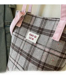 Detail showing high-quality plaid fabric texture and woven pink handle on tote bag
