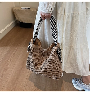 Détail du sac cabas en paille tressée avec poignées rayées et nœuds décoratifs élégants