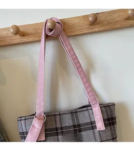 Close-up of retro plaid tote bag with pink shoulder straps and metal D-ring attachment