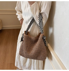 Détail du sac cabas en paille avec anses à rayures noires et blanches et nœud