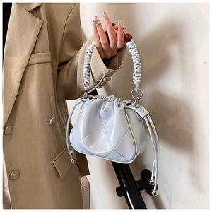 Detail of light blue pleated bucket bag with beaded circular handle and metal pendant