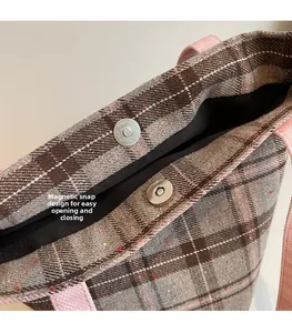 Detail view of the secure magnetic snap closure on the plaid vintage tote bag