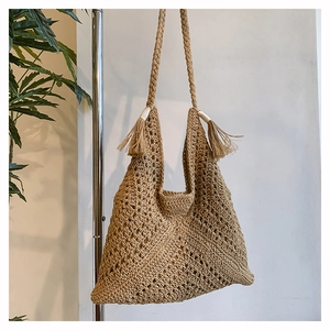 Detail of khaki crochet tote bag featuring bohemian tassels and braided shoulder straps