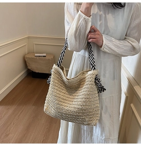 Détail d'un sac cabas en paille tissé main avec des anses en ruban noir et blanc