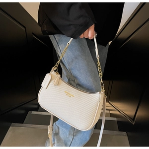 Détail du sac à bandoulière tressé crème avec chaîne dorée et logo sur la surface