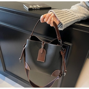 Detail of a retro color-block bucket bag showing black lychee texture and white stitching