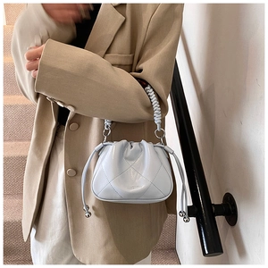 Detail shot of light blue bucket bag with diamond stitching and woven handle