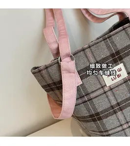 Close-up of pink canvas strap and stitching on vintage plaid fabric tote bag