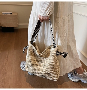 Détail du sac cabas en paille tressée avec nœuds décoratifs à rayures noires et blanches