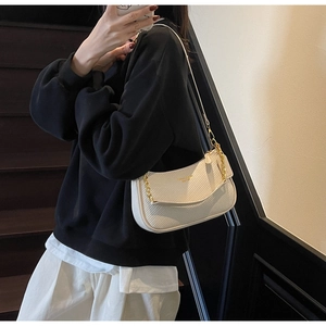 Détail d'un sac sous les bras blanc crème avec texture tissée et bandoulière dorée