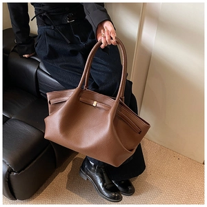 Close-up of brown litchi grain leather tote bag with elegant gold metal buckle and dual handles