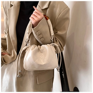 Detail of cream quilted bucket bag with woven handle and amber resin beads