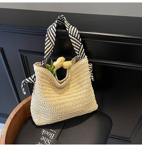 Détail du sac cabas en paille tressée avec anse en ruban rayé noir et blanc et déco tulipe