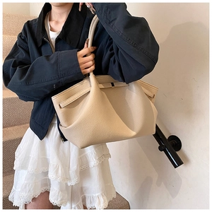 Detailed texture of beige pebbled leather tote bag worn by model in casual style