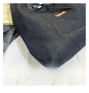 Détail de couture jaune de qualité et logo en cuir marron sur cabas en denim bleu
