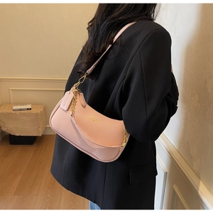 Détail du sac hobo rose en forme de croissant avec texture tressée et chaîne dorée