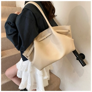 Close-up of a beige pleated leather tote bag showing grainy texture and elegant drape