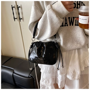 Detail of black quilted bucket bag with beaded handle and silver chain strap