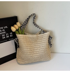 Détail d'un sac cabas en paille tissé avec poignées en tissu rayé et nœud pour la plage