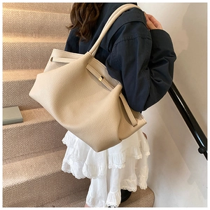 Close-up of cream pleated tote bag side detail with drawstring and metal buckle accents