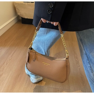 Gros plan d'un sac porté épaule marron tressé avec bandoulière chaîne et logo doré