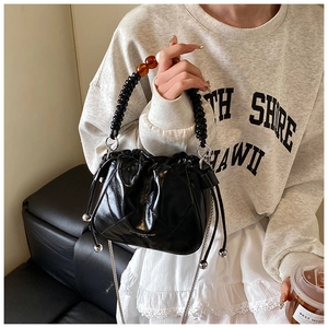 Detail of black drawstring bucket bag with bead handle and silver chain strap close-up
