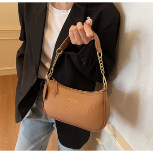 Détail d'un sac baguette tissé marron avec chaîne dorée et lettrage du logo
