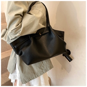 Close-up of black lychee-grain leather tote bag with elegant gold metal buckle detail