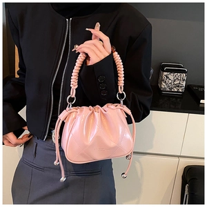 Close-up of pink quilted bucket bag featuring woven handle and metallic orb charm