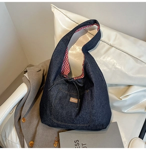 Détail du sac cabas en denim bleu avec doublure à carreaux rouges et étiquette de marque