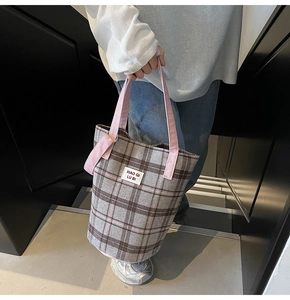 Detail of checkered tote bag with pink straps and brand label on indoor stairs