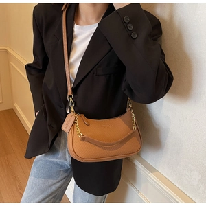 Détail d'un sac hobo marron texturé avec chaîne en métal et bandoulière en cuir réglable