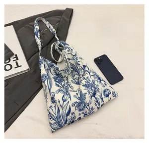 Detailed comparison of embroidered canvas tote bag size with smartphone and books