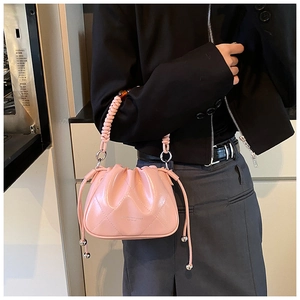 Detail of light pink bucket bag with pleated faux leather and braided rope handle