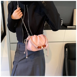 Detail of pink ruched bucket bag featuring silver chain and woven handle with amber beads
