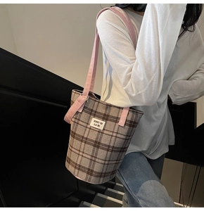 Close-up of retro plaid tote bag with pink straps worn by a model in casual style