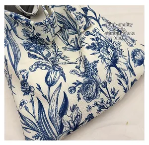 Close-up of premium floral canvas fabric showing soft texture and blue embroidery
