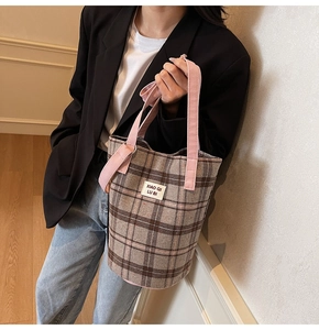Detail of vintage plaid tote bag with pink canvas handles and branded white label patch