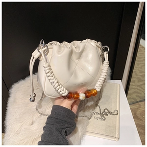 Detail of cream drawstring bucket bag with woven handle and amber decorative beads